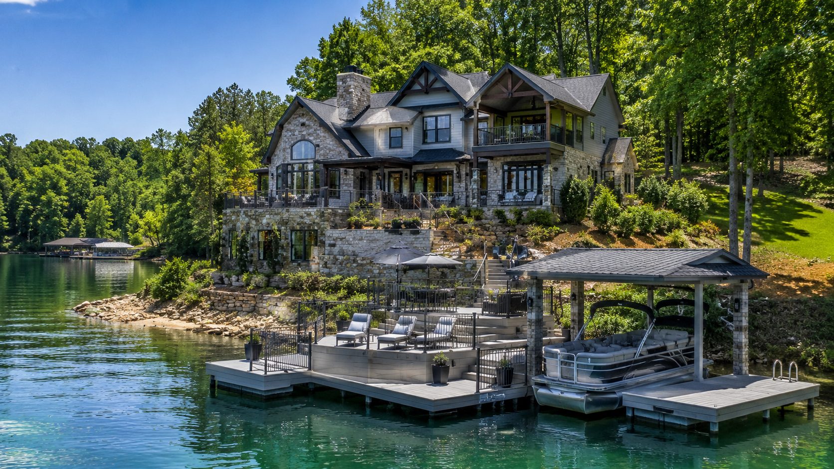 Norris Lake waterfront retreat with stone architecture, private dock, pontoon boat, wooded privacy, and blue-gray details.